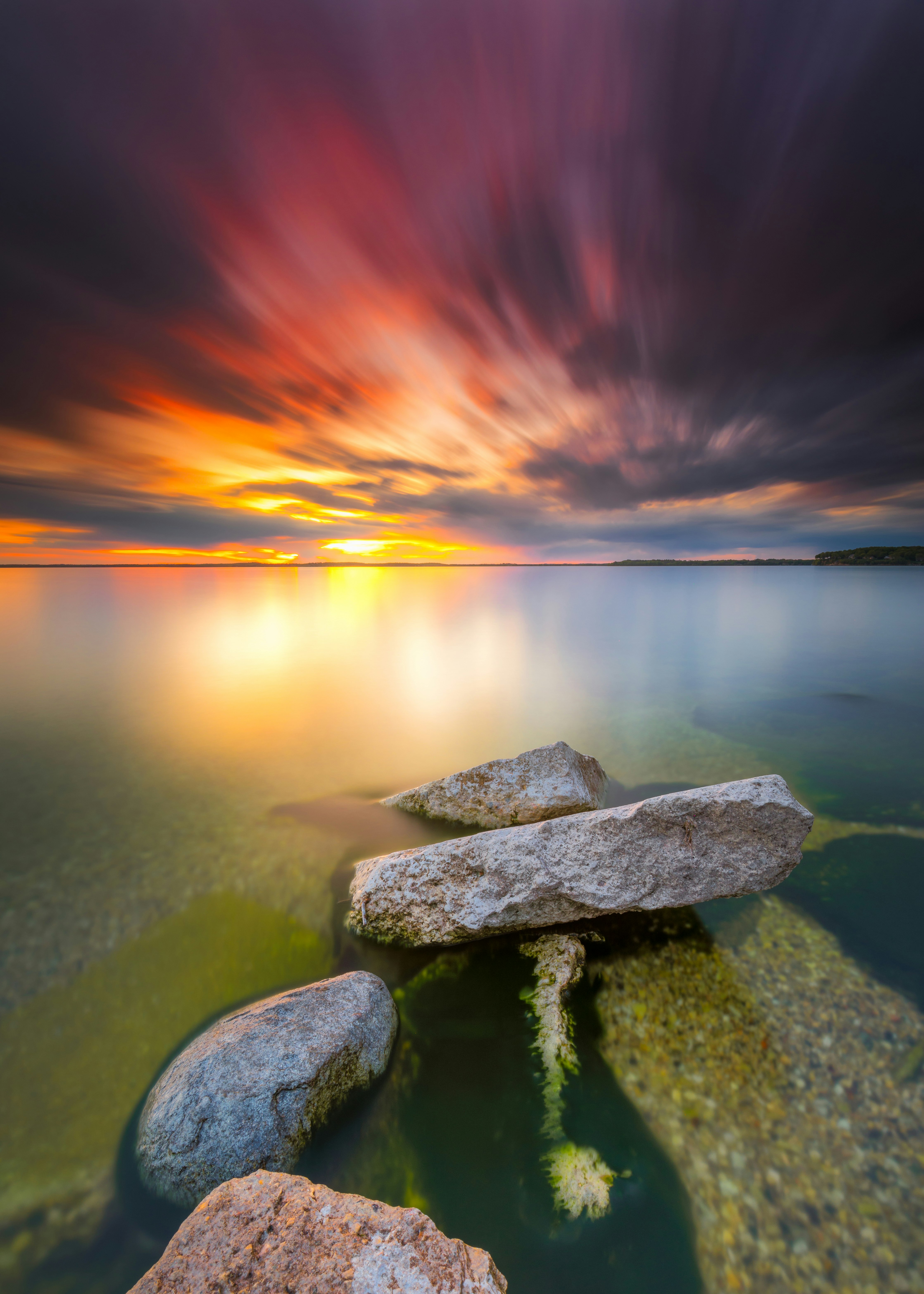 gray rock on body of water during sunset